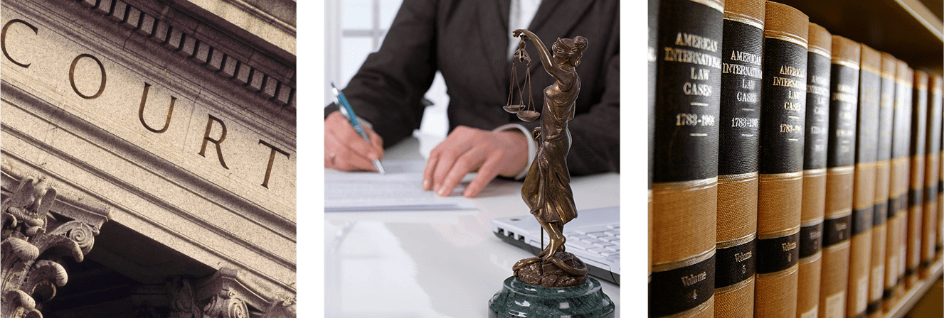 A person writing on paper next to a statue of lady justice.